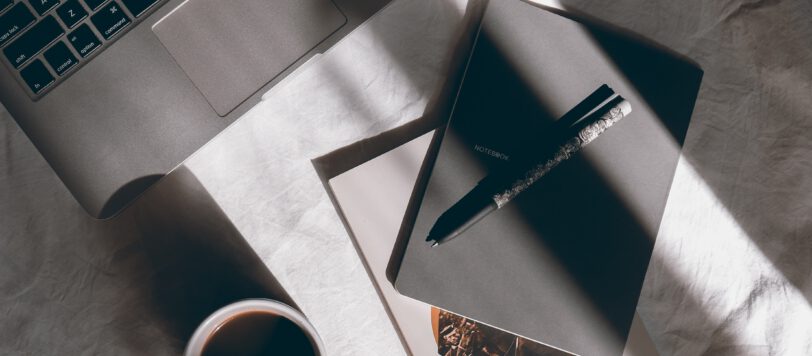 Laptop, Notizbücher und Tasse Kaffee auf einem Tisch