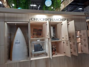 the back of the Swiss space agency's booth: a set of wooden cupboards containing hardware models and the heading "Chuchichäschtli"